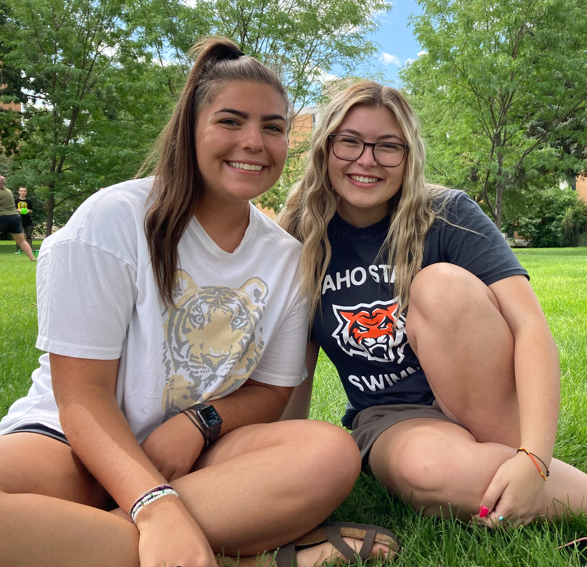 Two girls sit on the grass.