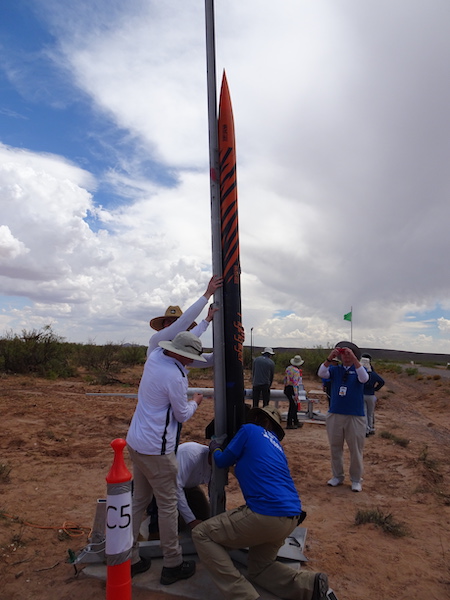 Two students hold up a large rocket .