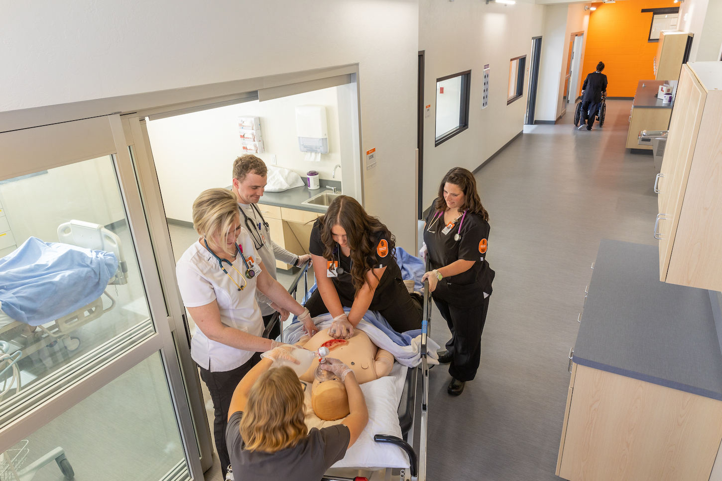 Students perform a procedure on a simulated patient