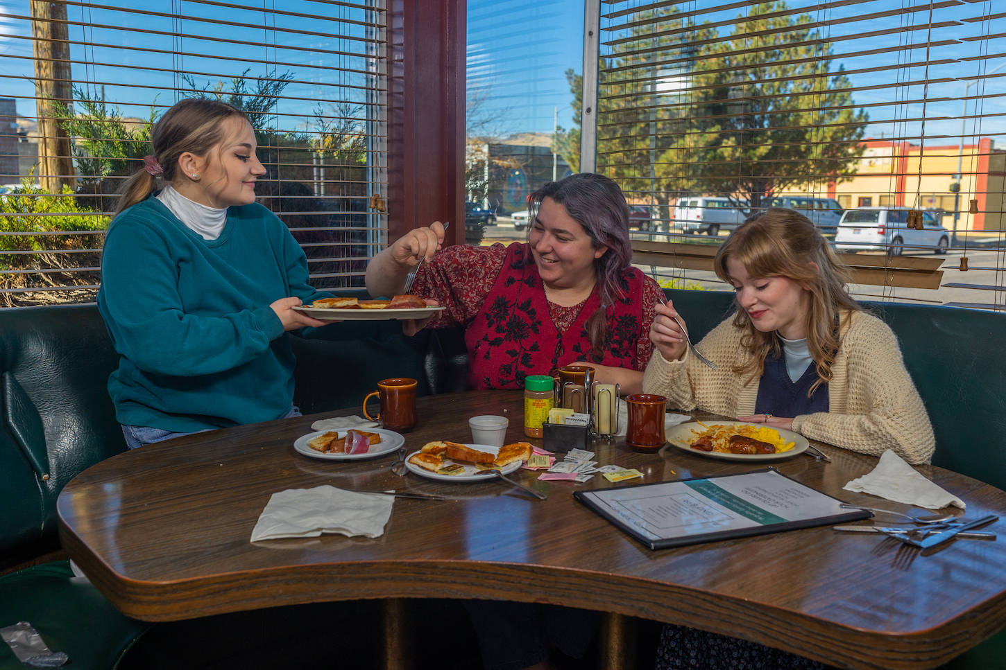 Three girls sit in a diner