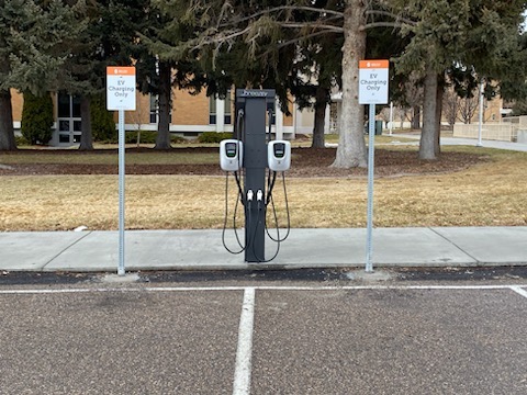 An electric vehicle charging station between two signs.