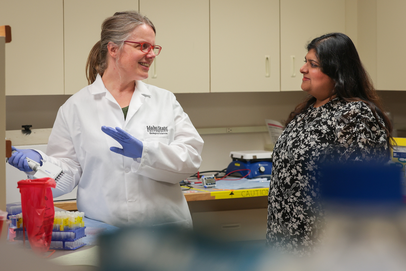 Anne Koski talks with a researcher in a laboratory