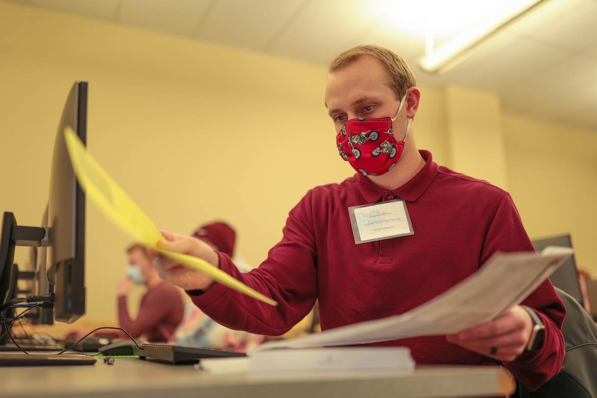 A man in a red shirt sorts paperwork.