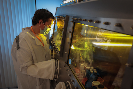 A student works in a laboratory using a glove box