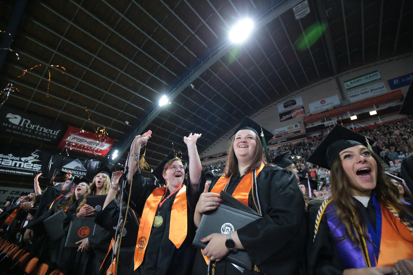 A group of women in commencement regalia cheering