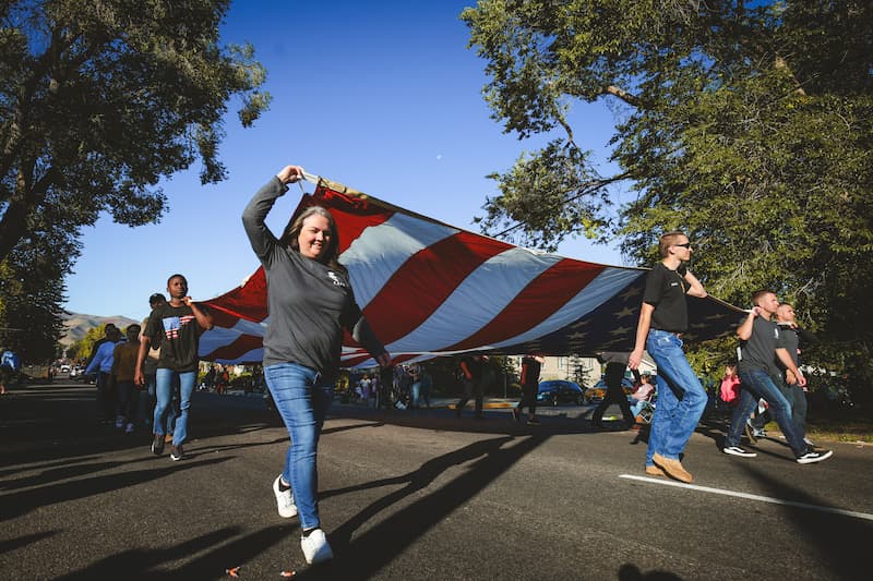 A group of students carry a large American Flag at a parade