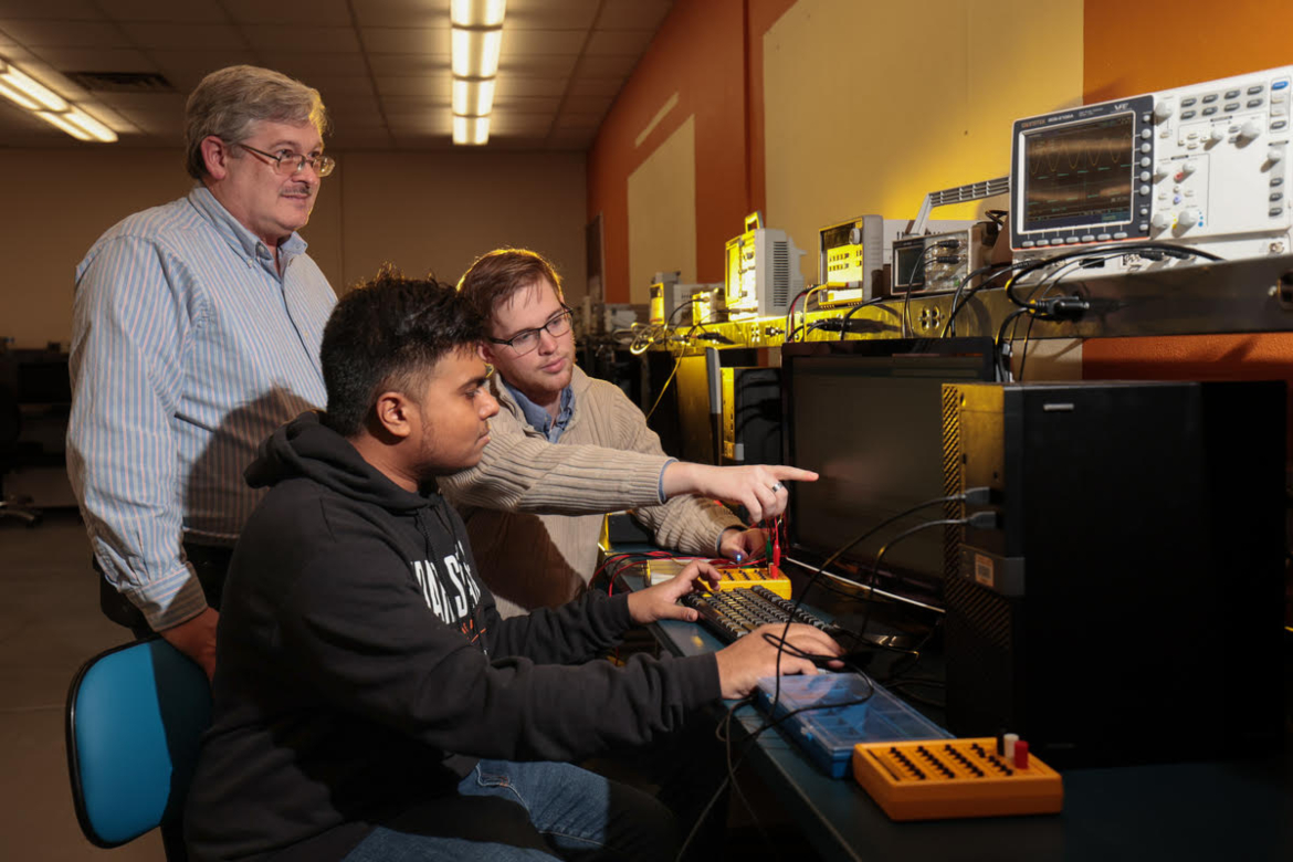 A group of students look at a computer