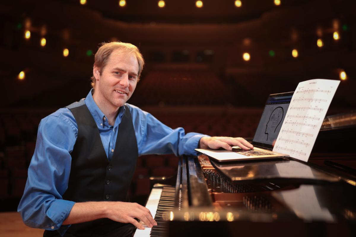 Paul Bodily sits at a piano