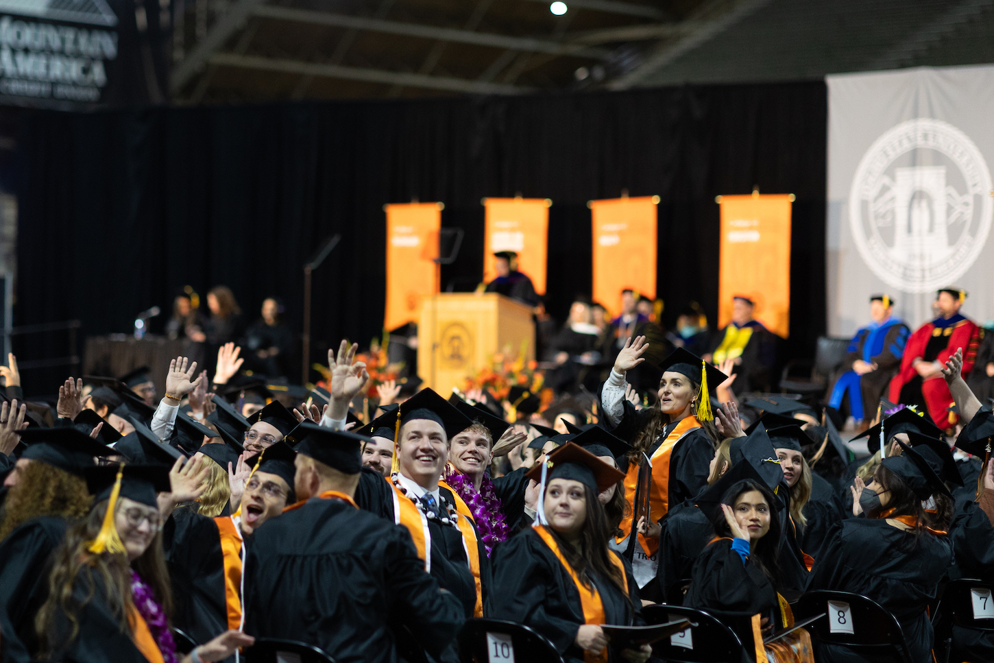 Students in caps and gowns look to the crowd