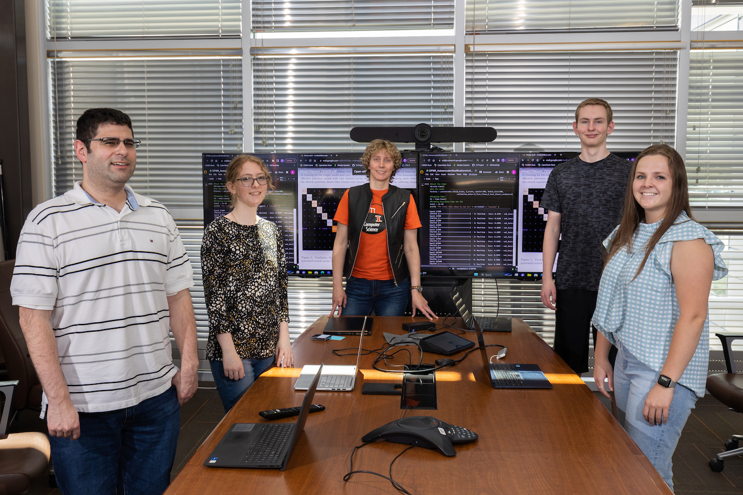 Four adults stand around a computer