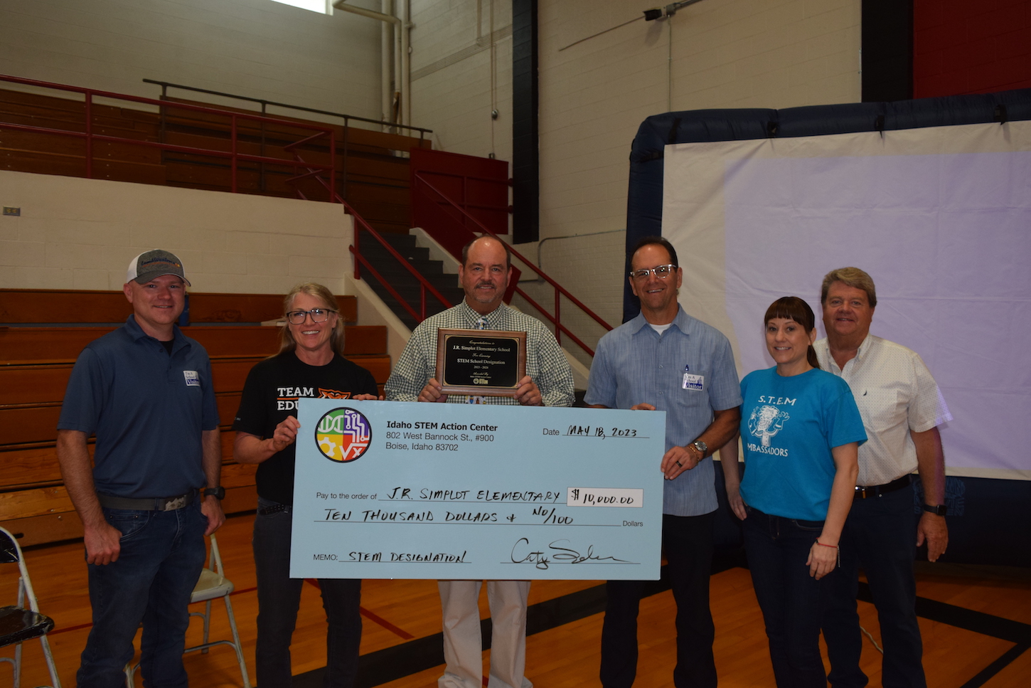 A group of teachers and community members hold a giant check