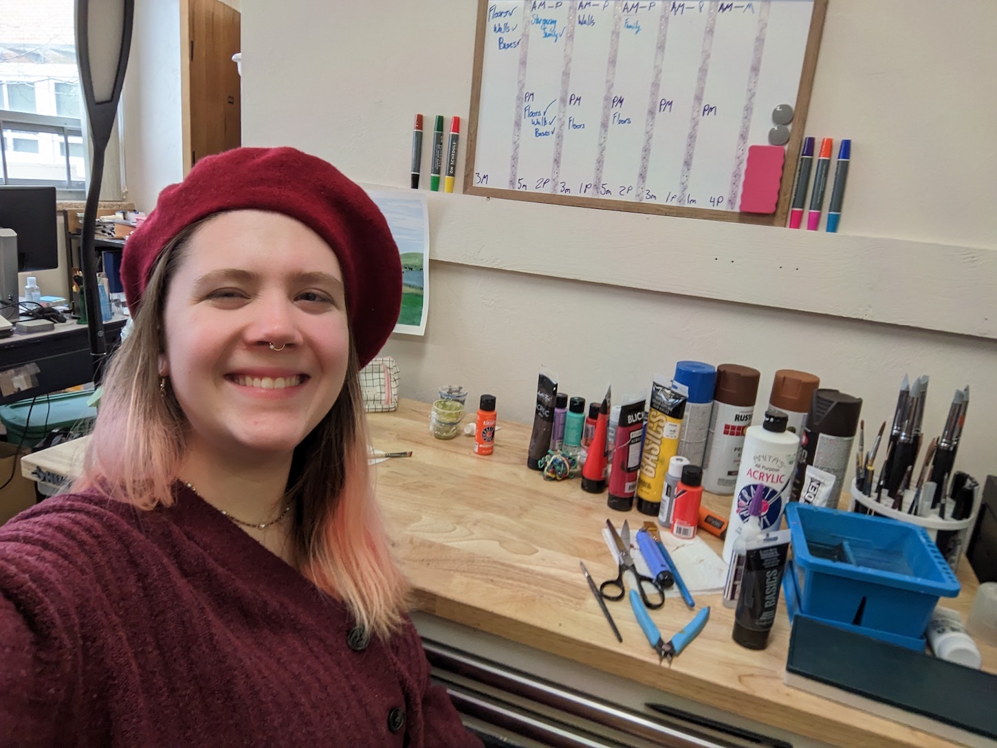 A woman sits next to a set of paints