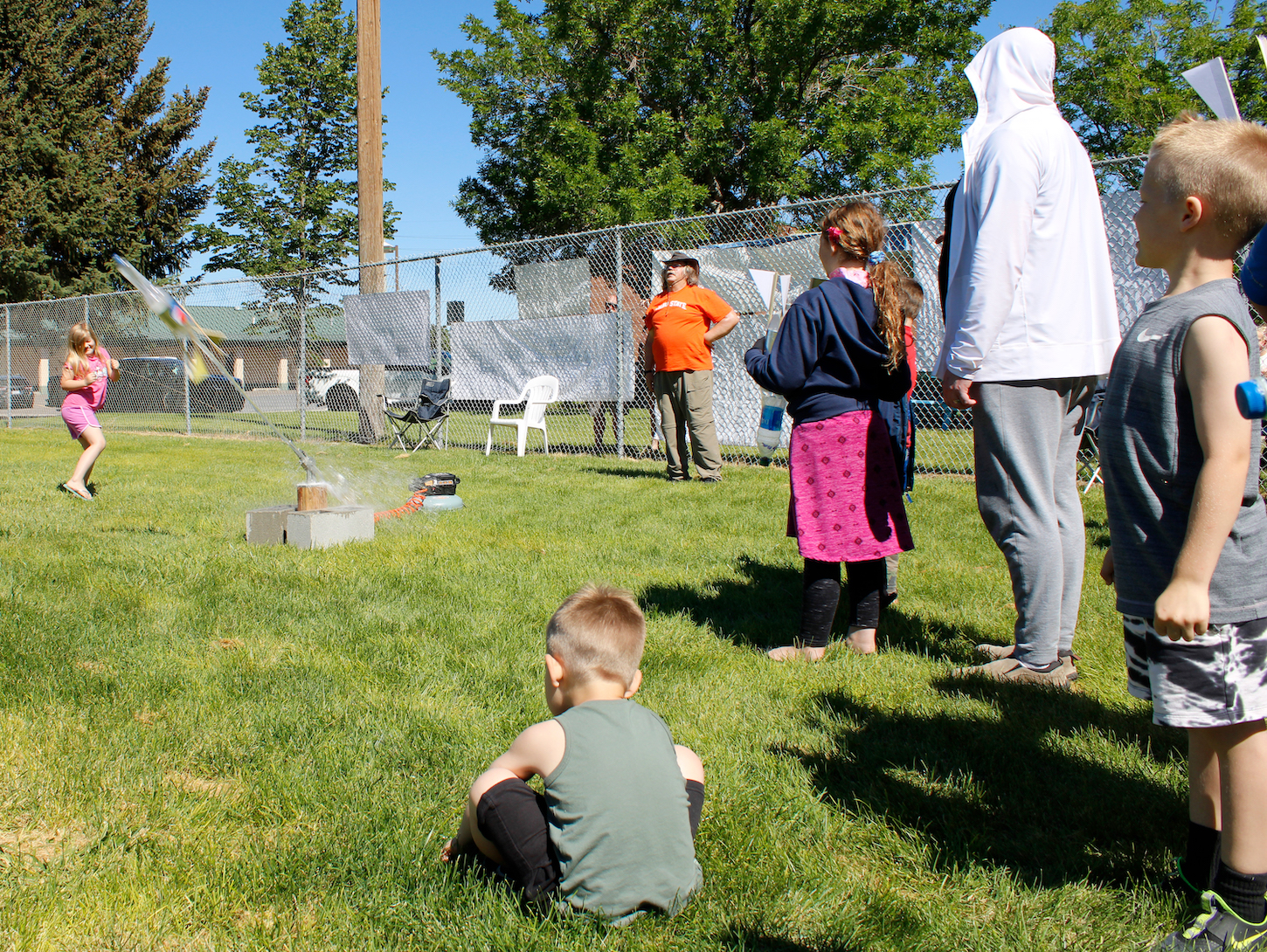 Three kids shoot off water rockets in a park