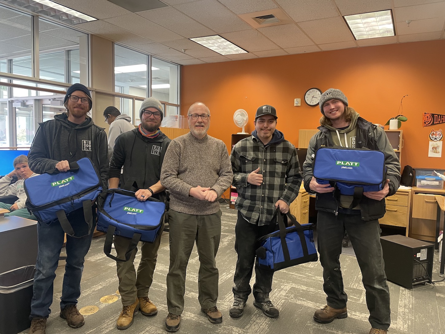 Five men hold donated tool bags