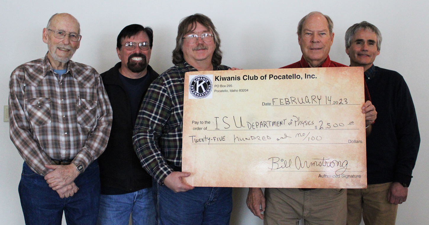 Three men hold a giant check