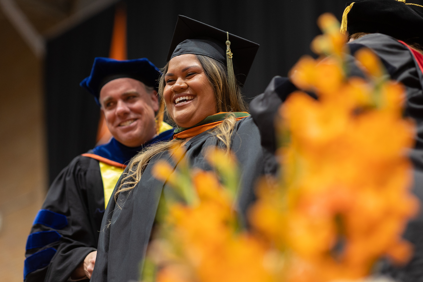 A woman smiles as a hood is placed around her neck.