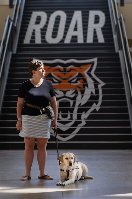 Quincie Mattick and her dog stand near the stairs at the Rendezvous Building