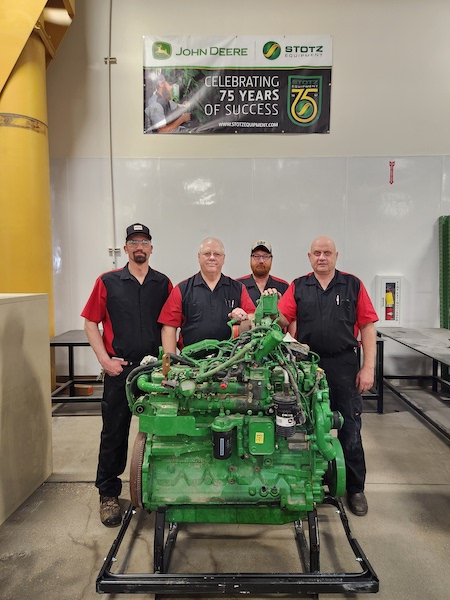 Four men stand next to heavy machinery