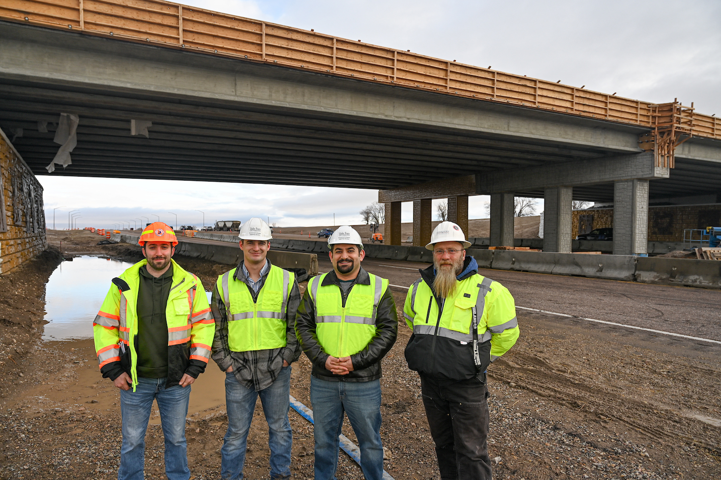 A group of men stand by a bridge