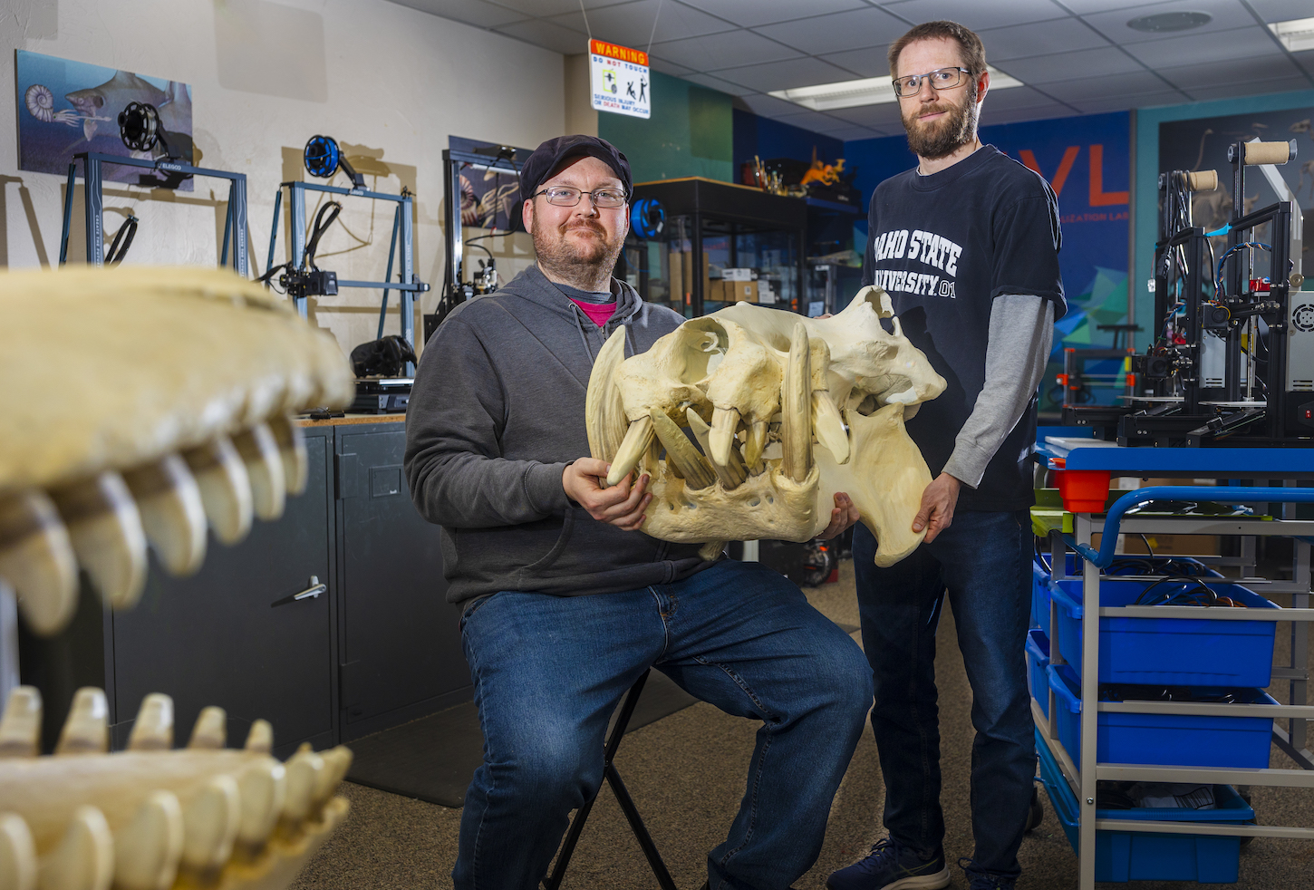 Two men hold a giant skull