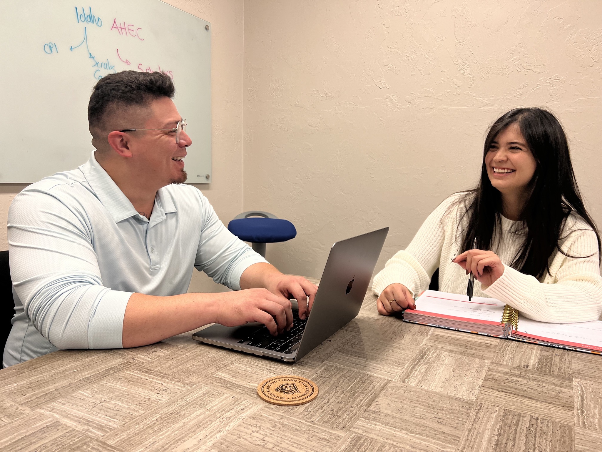 A man with a computer talks with a woman