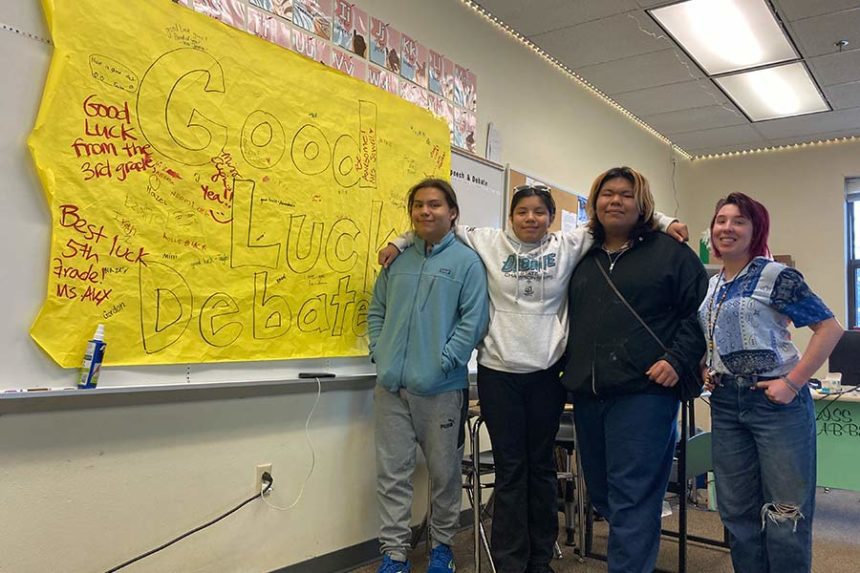 Members of the Shoshone-Bannock High School Debate Team pose near a display board