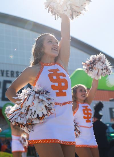 ISU cheerleader with pom pom in the air outside of Holt Arena