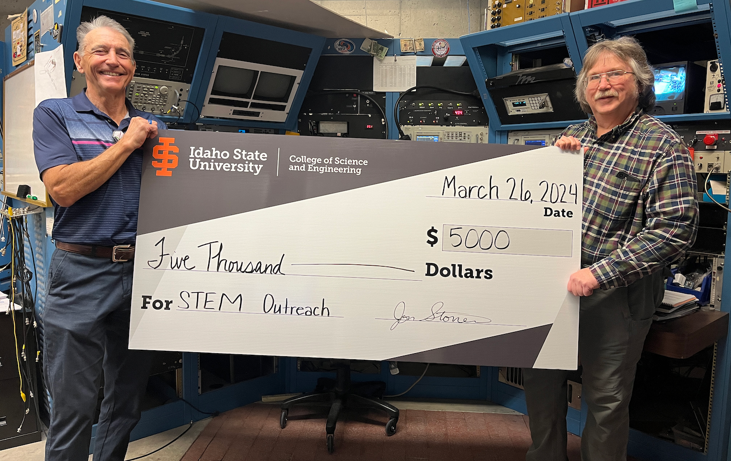 Two men hold a large check
