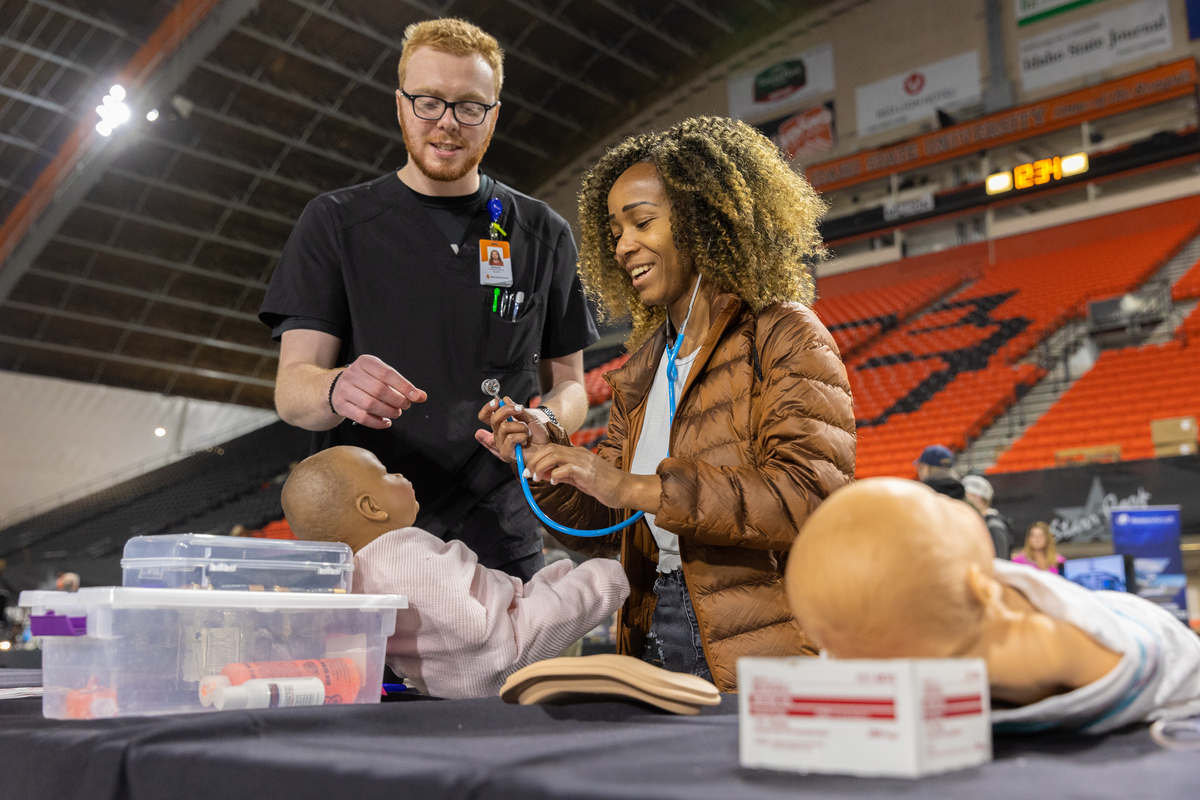 a student interacts with an infant simulation manikin at a booth during the Tech Expo event in the ICCU Dome