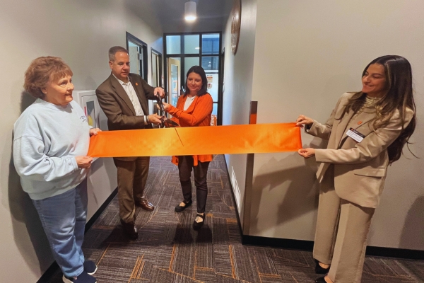 Two people hold a ribbon at the Magnuson ribbon cutting