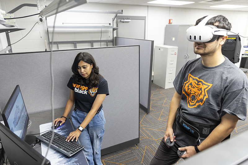 Reece Foulkrod (right), ISU student, plays Lit-VR, a virtual reality game based in 17th-century London, while Farjana Eishita, assistant professor at Idaho State University, looks on