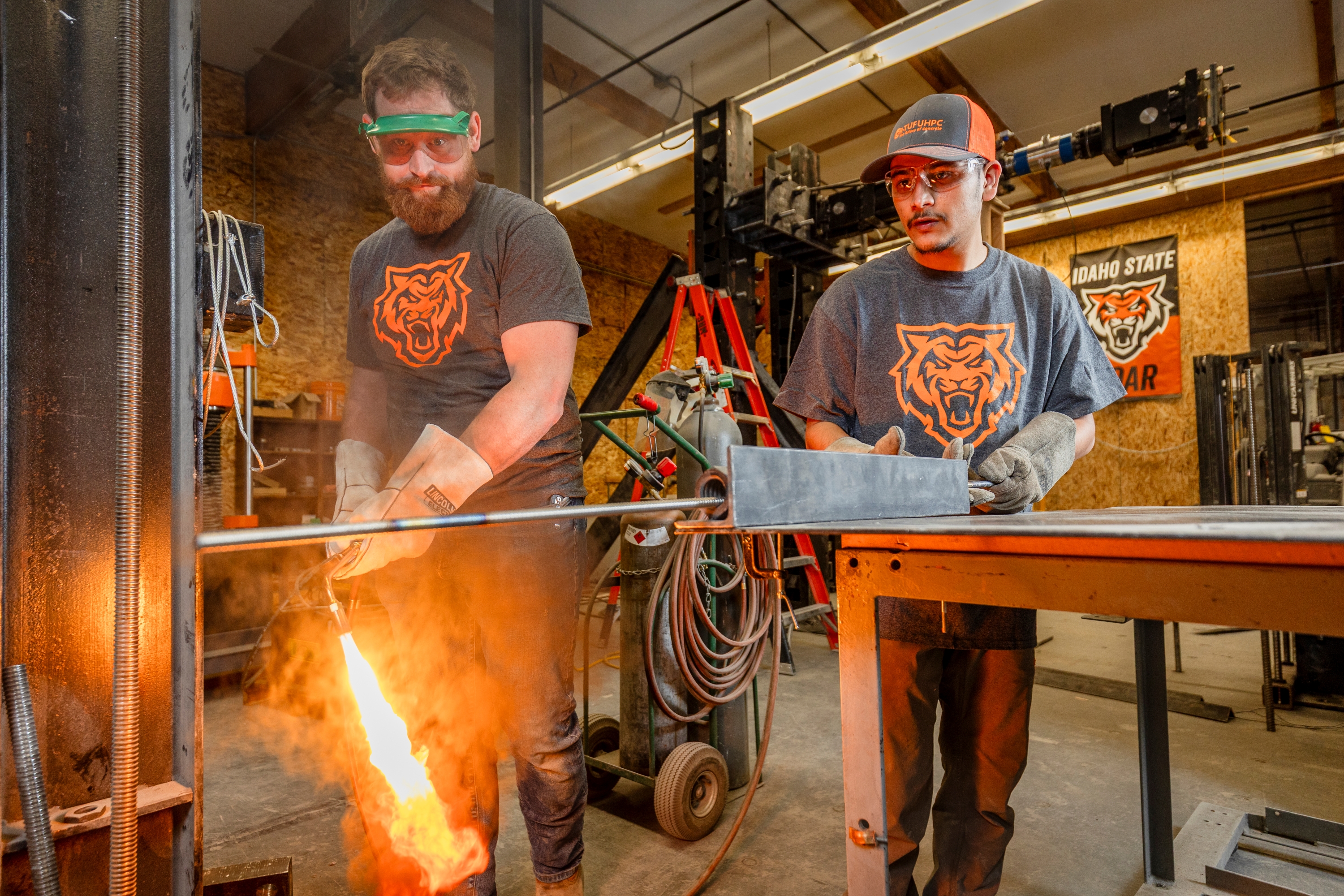Joe Shurtleff, laboratory supervisor, heats a titanium alloy bar while Sujan Timsina looks on.
