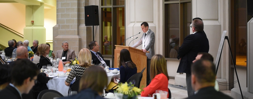 A scene from last year's Business Leader of the Year Award banquet of person speaking at podium to people at tables.