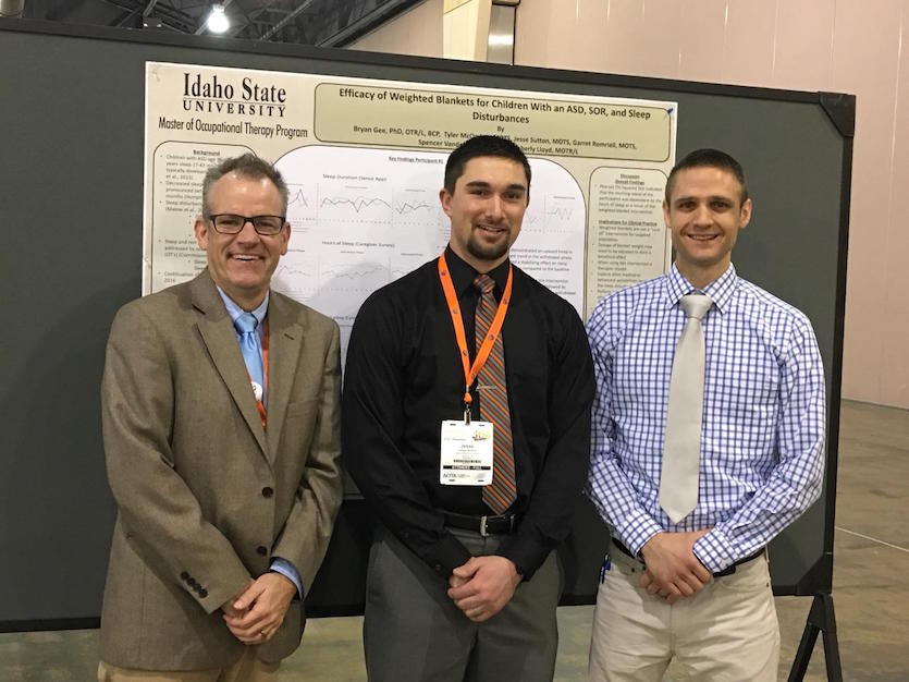 Two occupational therapy students and their instructor standing in front of research poster. 