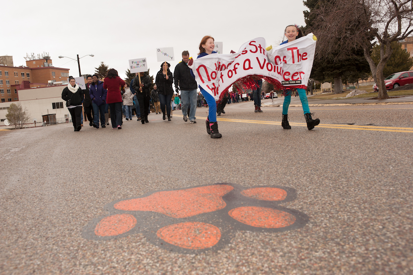 Marchers in last year's march heading up Martin Luther King Jr. Drive, with a Bengal paw print in the foreground.