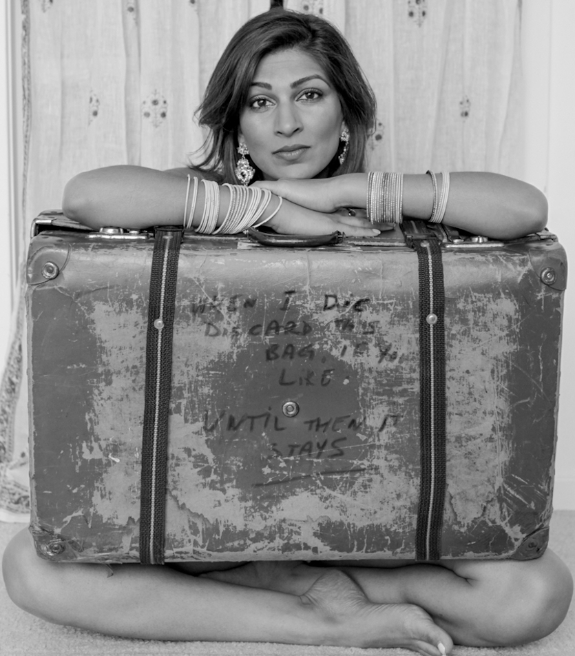 Photo of Minita Gandhi sitting behind a suitcase. 