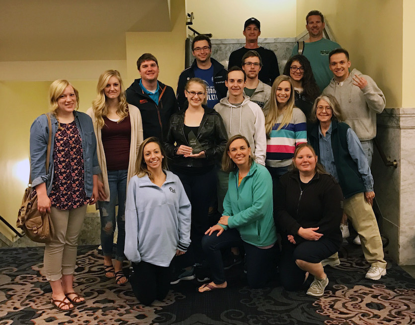 Group picture of 16-person ISU advertising team with awards. 