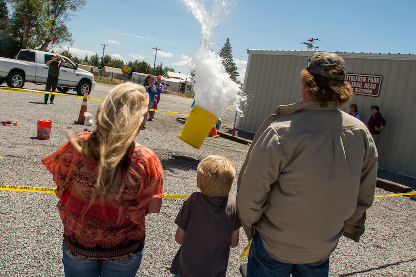 A picture of an explosion going off in a trash can with people in the foreground looking on at the 