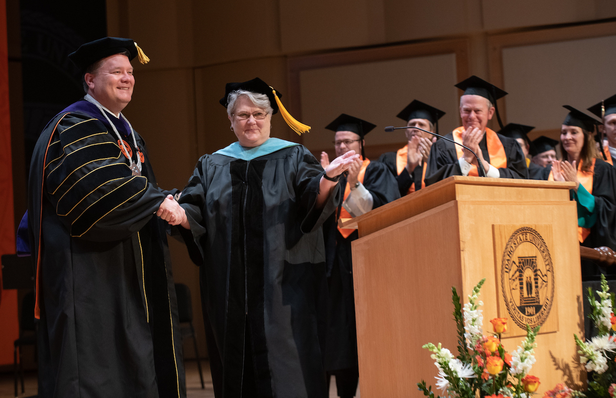 ISU President Kevin Satterlee being welcome as 13th University president b Idaho State Board of Education member Linda Clark as Gov. Little and other platform guests look on. 