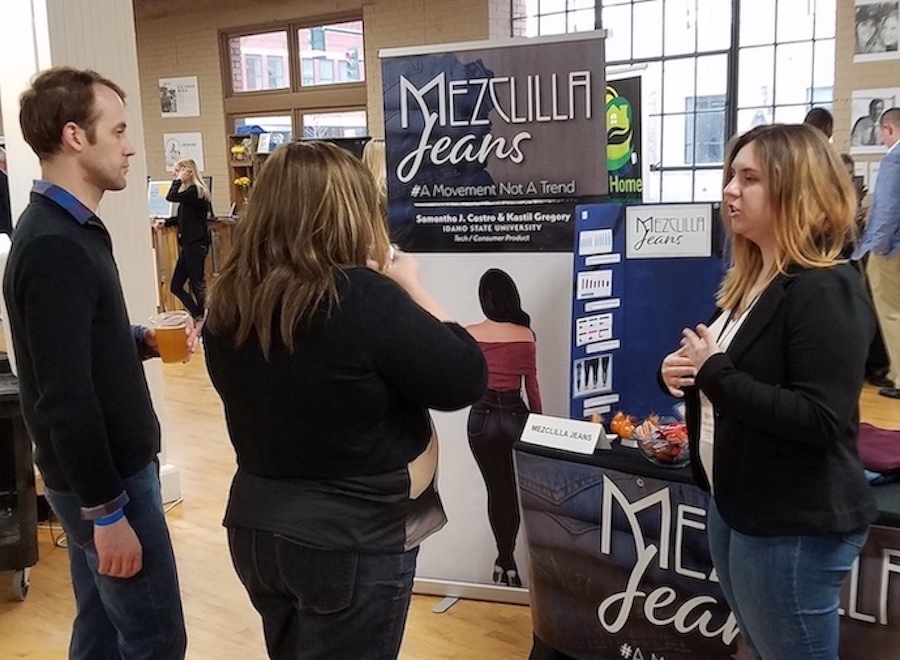 Student at table talking to two people at Idaho Entrepreneur Challenge.