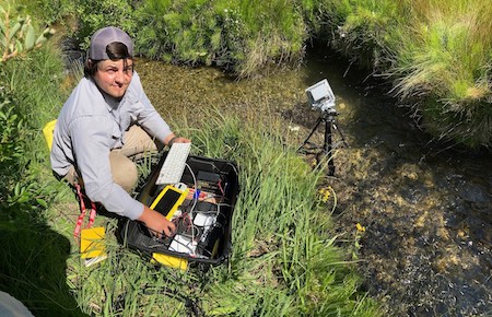 Zane Stephenson setting up cameras by creek.