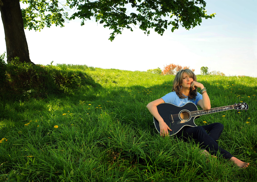Kathy Mattea photo with her sitting in field with her guitar