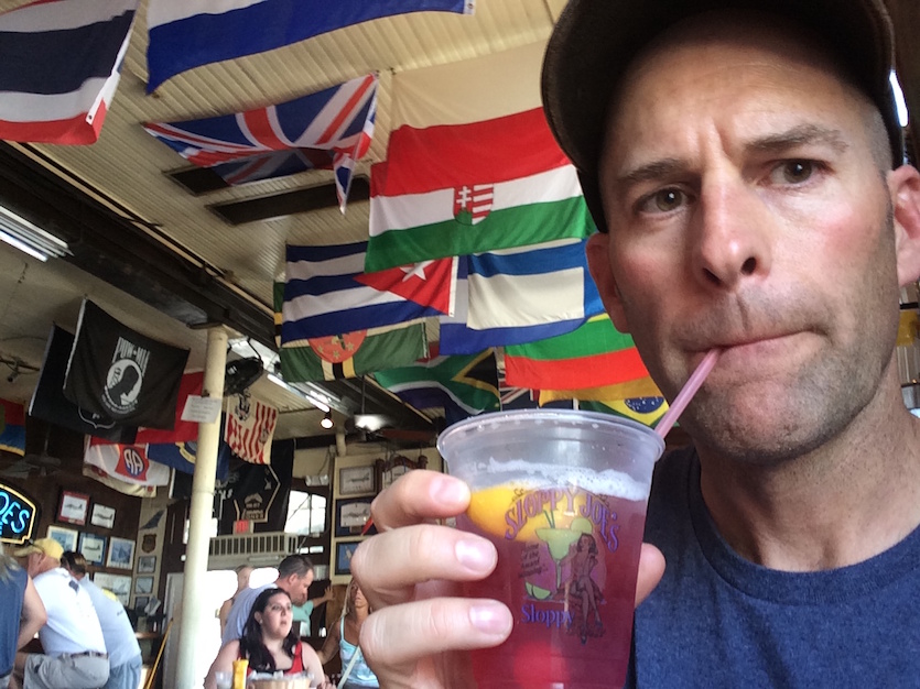 A photo of author James Babcock drinking from a glass with a straw.