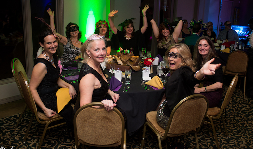 Photo of women at 2016 benefit in ball attire sitting at a table.