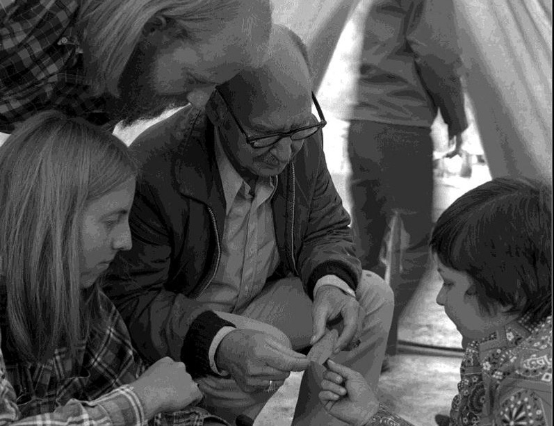 Dr. Crabtree, surrounded by four onlookers, holding an arrowhead.