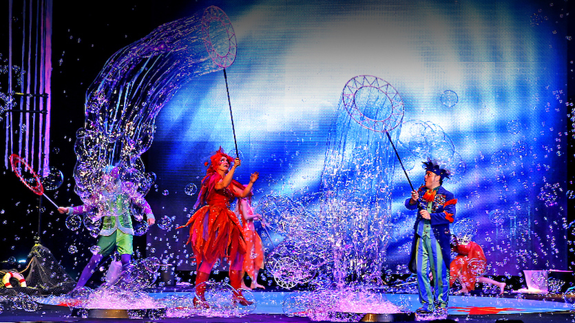 A scene from production of performers on stage making large bubbles.