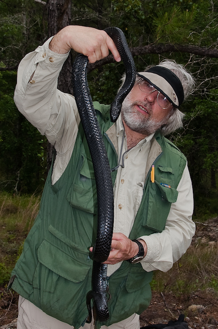 Photo of Chuck Peterson holding a large snake. 