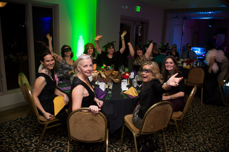 Photo of women dressed up for masquerade ball at a table.