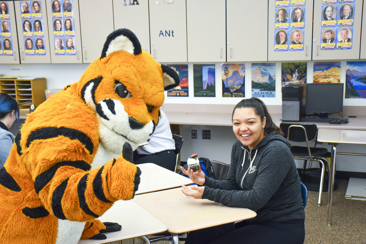 Benny the Bengal gives a cupcake to a student at Century High School.