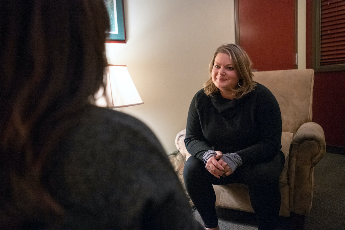 A counselor in background facing the silhouette of a patient in the foreground.